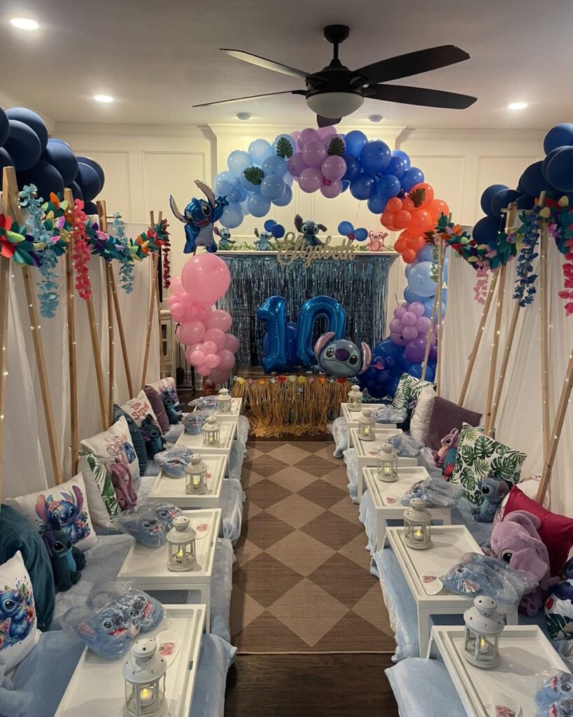 Indoor birthday party setup by a South Florida party shop, featuring low tables, white trays, lanterns, themed pillows, a balloon arch, and a “10” balloon display under a ceiling fan.